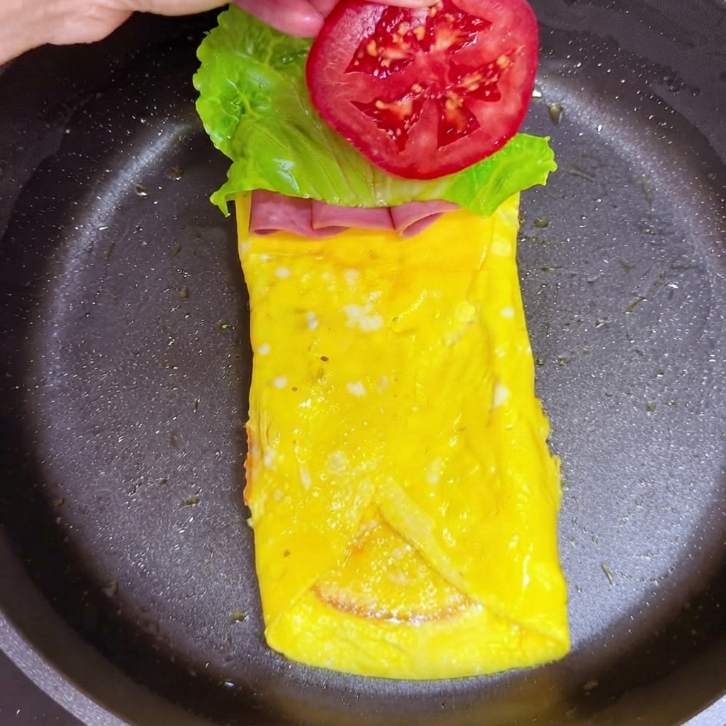 Une tranche de tomate rouge ajoutée sur le dessus de la couche de feuille de laitue.