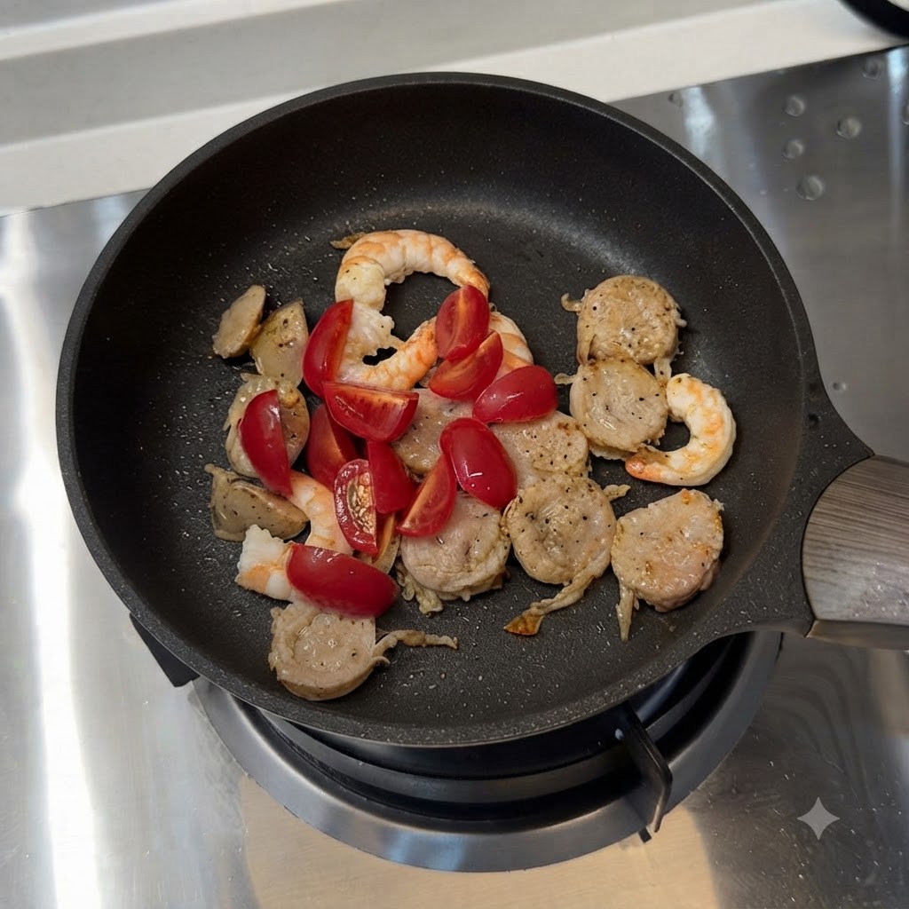 Tomates cerises et poivrons verts tranchés mélangés avec la saucisse et les crevettes dans une poêle.
