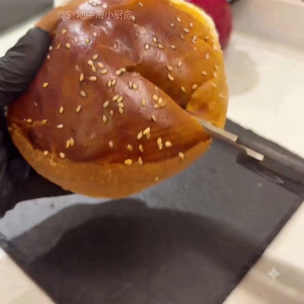 Un pain à hamburger coupé en deux avec des ciseaux de cuisine, dont la mie tendre est en train dêtre retirée.