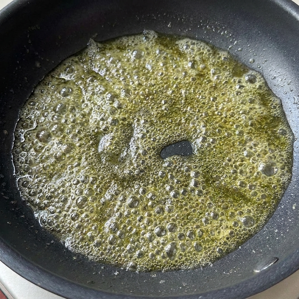 De la sauce soja claire et du concentré de tomate ajoutés au beurre fondeur bouillonnant dans une poêle.