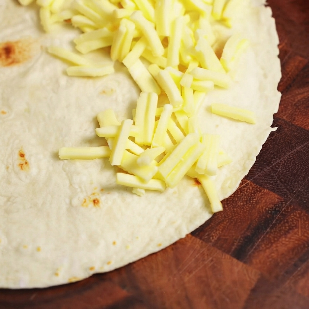 Garniture de bœuf cuite et fromage mozzarella disposés sur une moitié dune tortilla de blé plate.