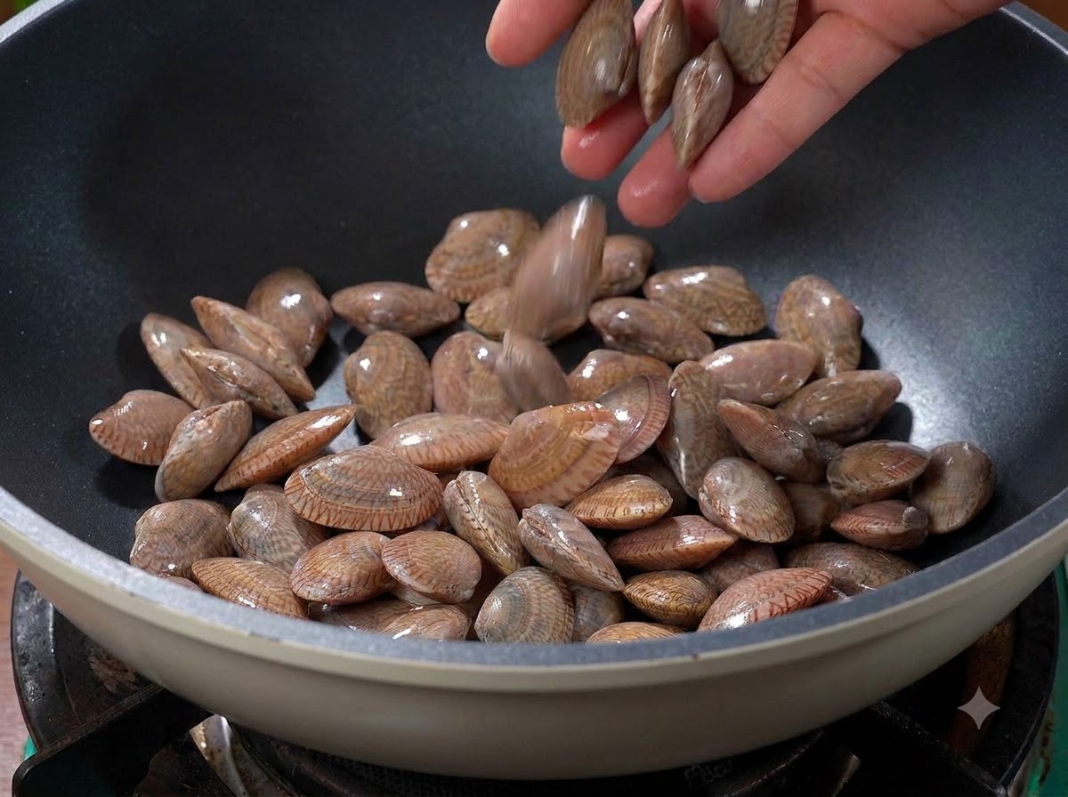 Palourdes jetées dans un wok chaud et sec sur la cuisinière.