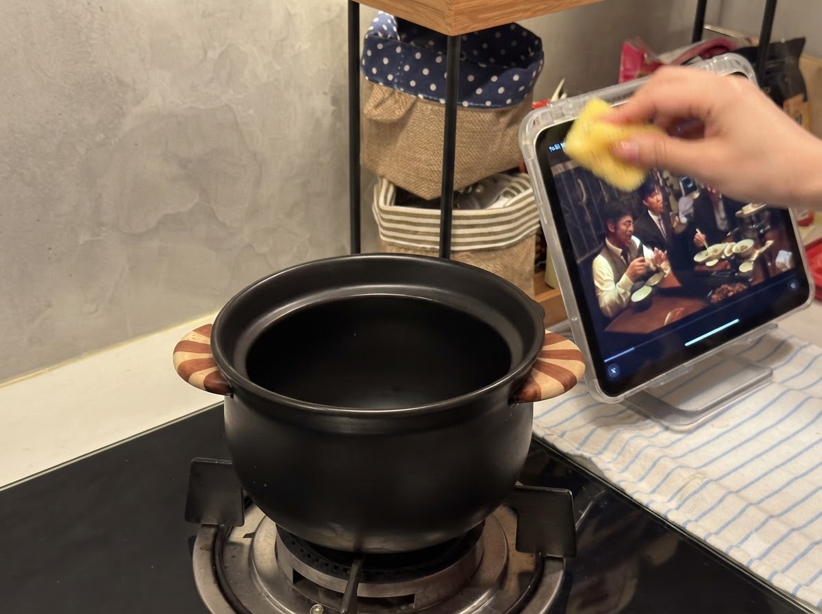 Un petit pot en céramique noire posé sur le brûleur dune cuisinière à gaz.