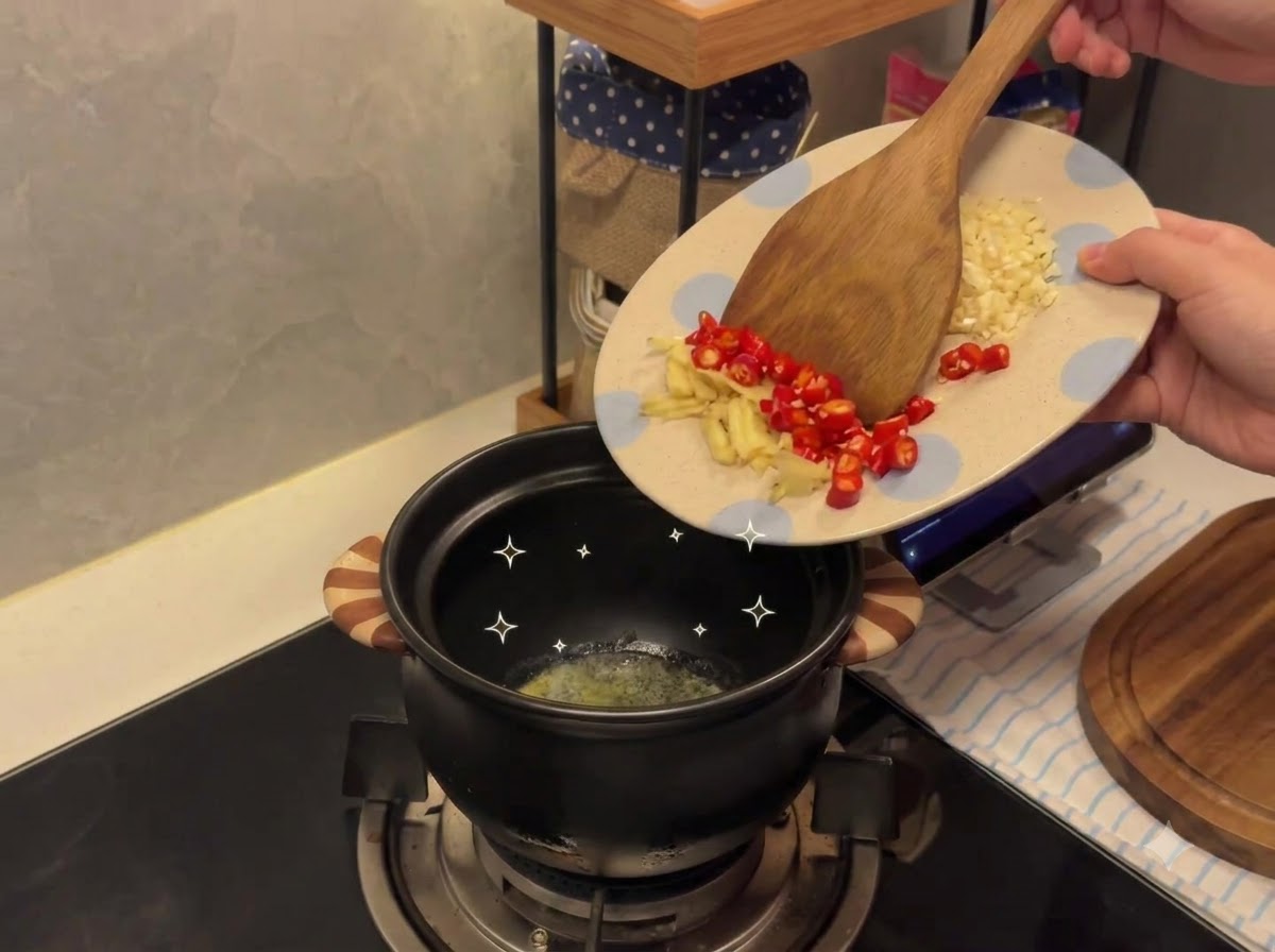 Ail haché et piments transférés dune assiette à motifs vers un pot en céramique contenant du beurre fondu.