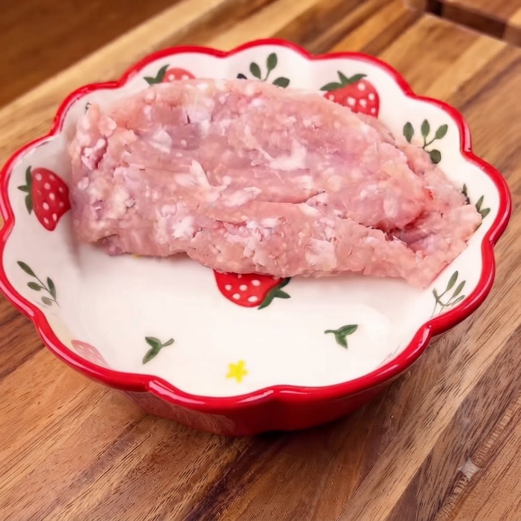 Porc haché placé dans un bol fleuri avec des oignons verts hachés sur le dessus.