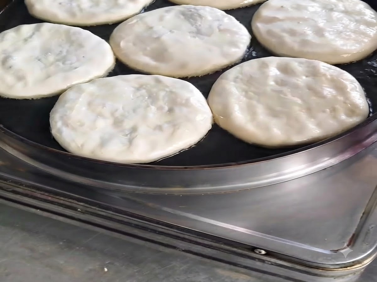 Plusieurs galettes de viande en train de cuire dans une poêle avec un filet dhuile versé sur le dessus.