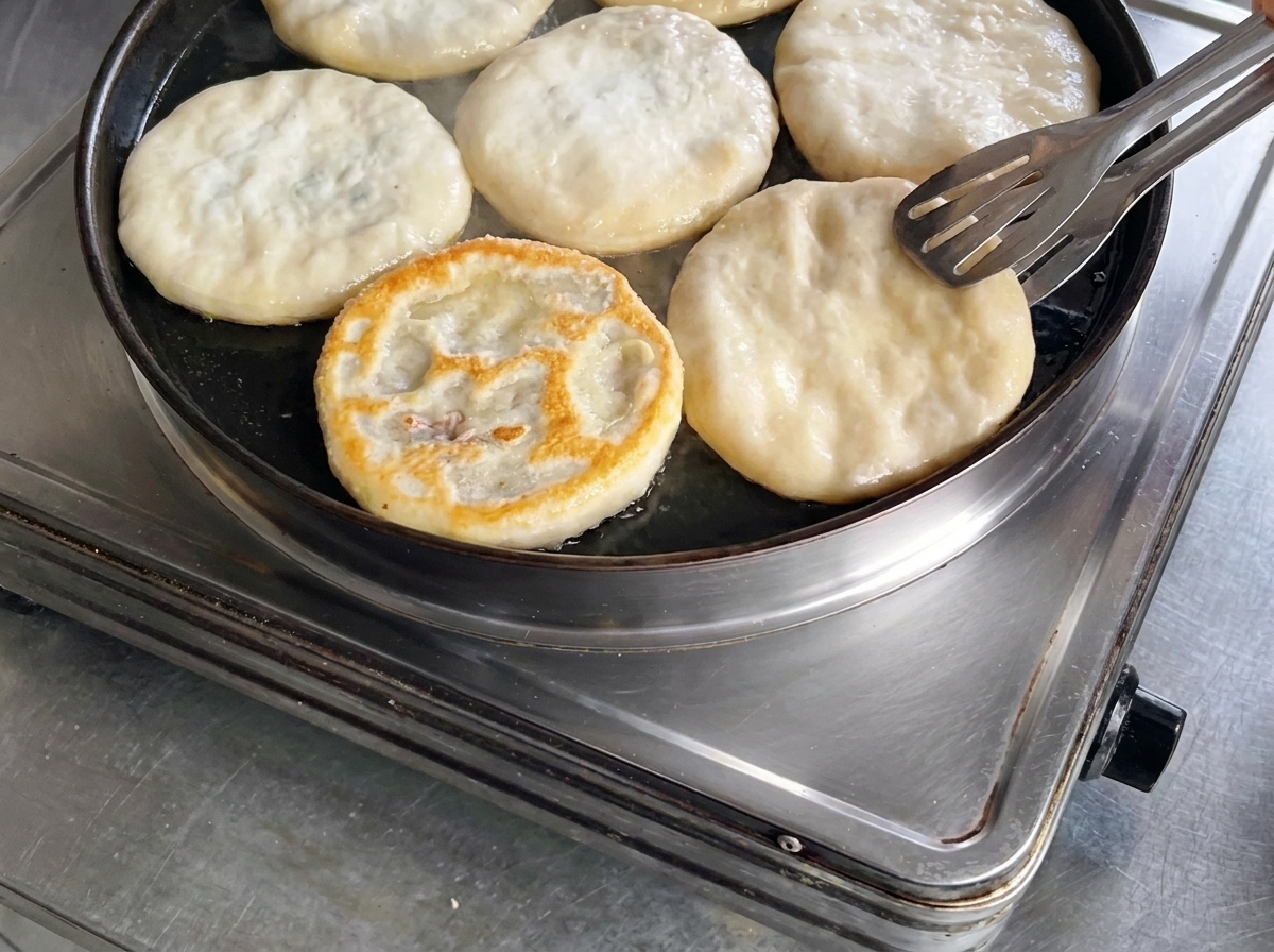 Lutilisation dune pince pour retourner une galette de viande dans une poêle, révélant une surface bien dorée.