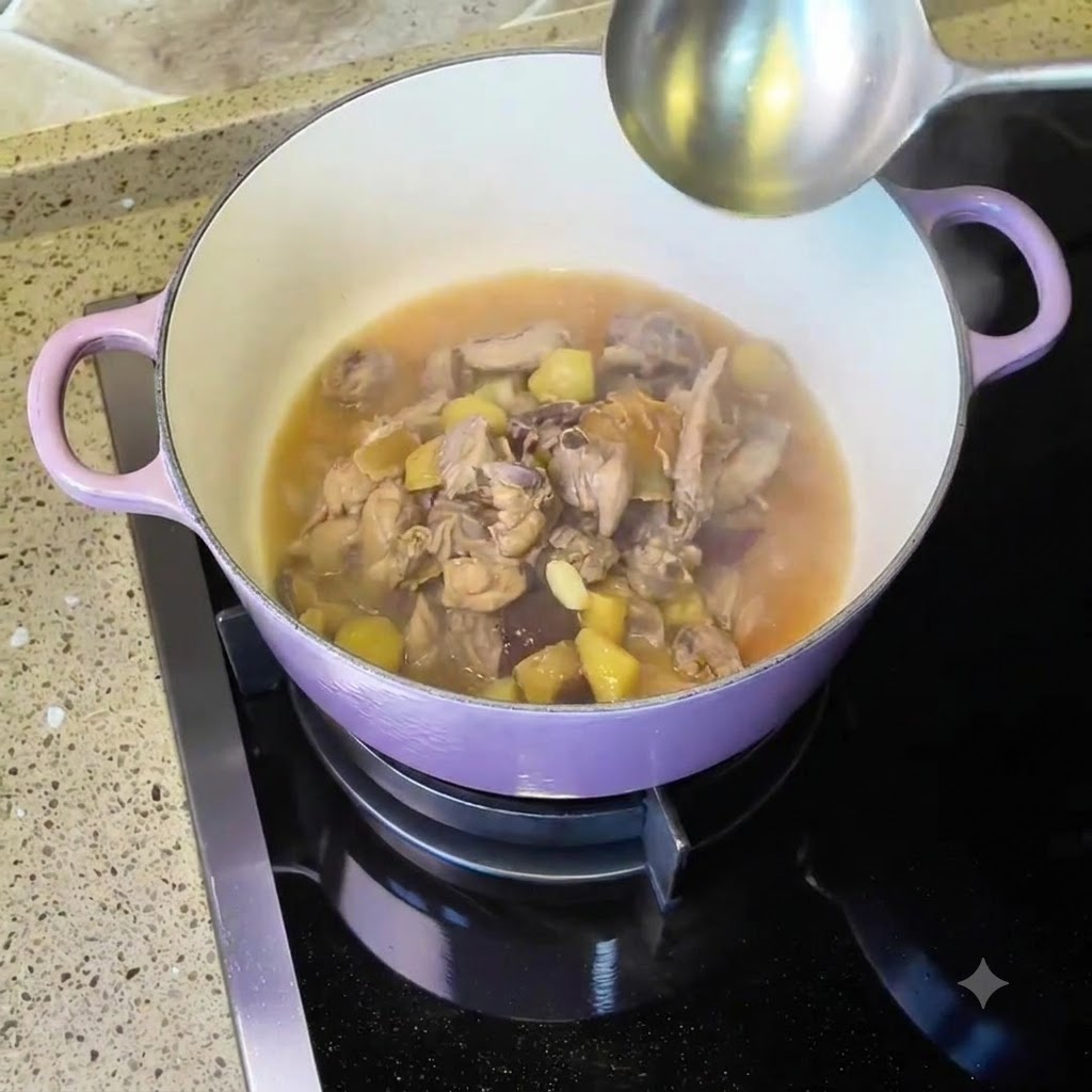 Du poulet et de la soupe mijotant à lintérieur dune cocotte en fonte émaillée violette sur la cuisinière avec une louche à proximité.