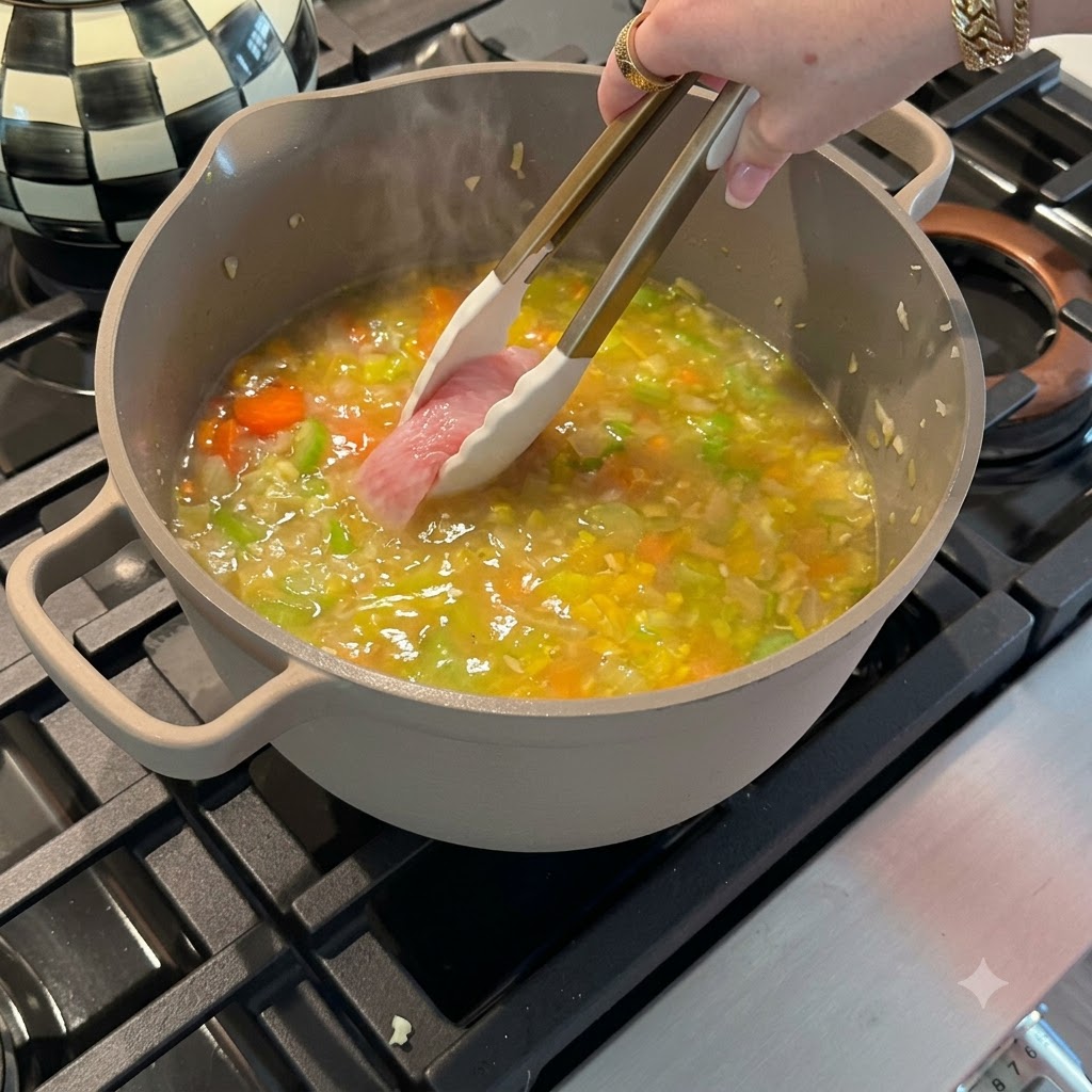 Des filets de poitrine de poulet crus déposés dans une marmite de bouillon de légumes frémissant à laide de pinces à embout en silicone.