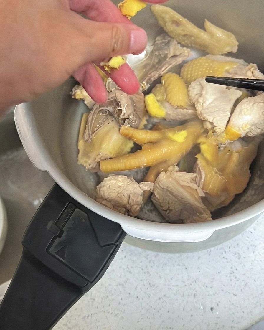 Morceaux de gingembre écrasés éparpillés sur le poulet à lintérieur dun autocuiseur.