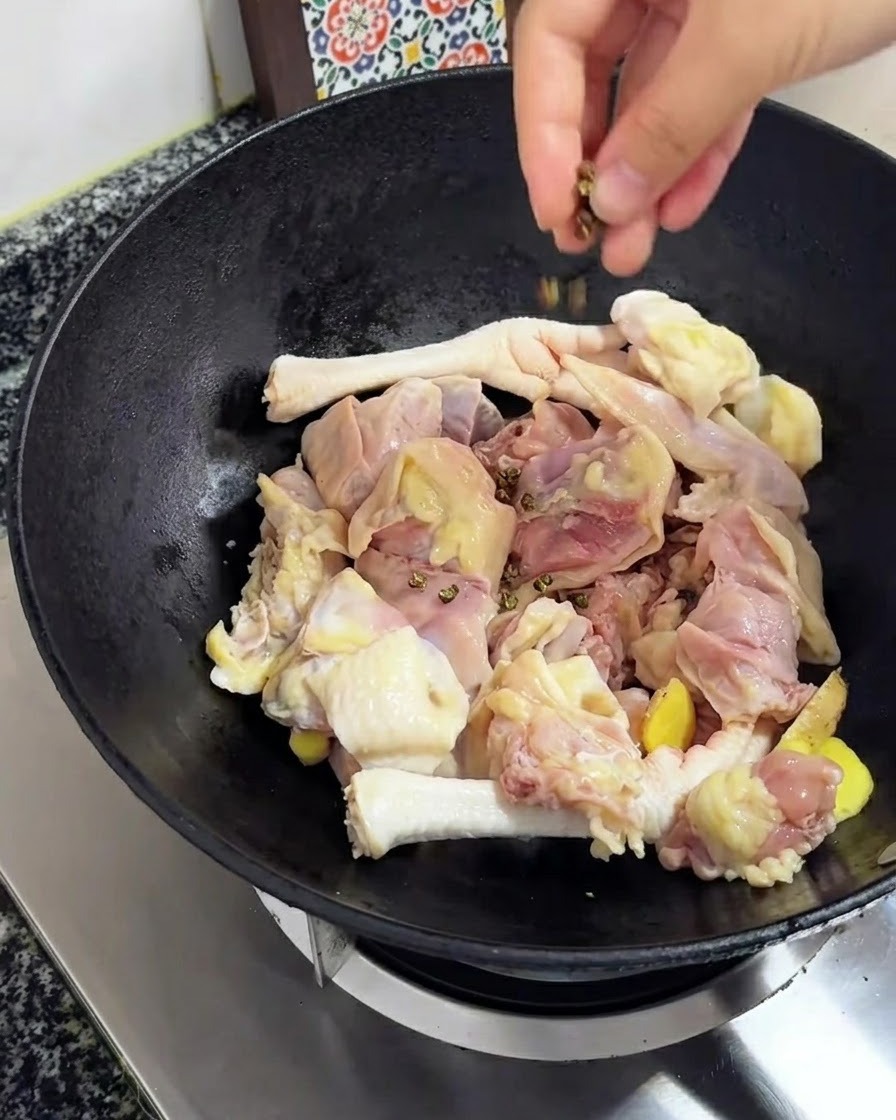 Baies de Sichuan jetées sur le poulet et le gingembre dans le wok.
