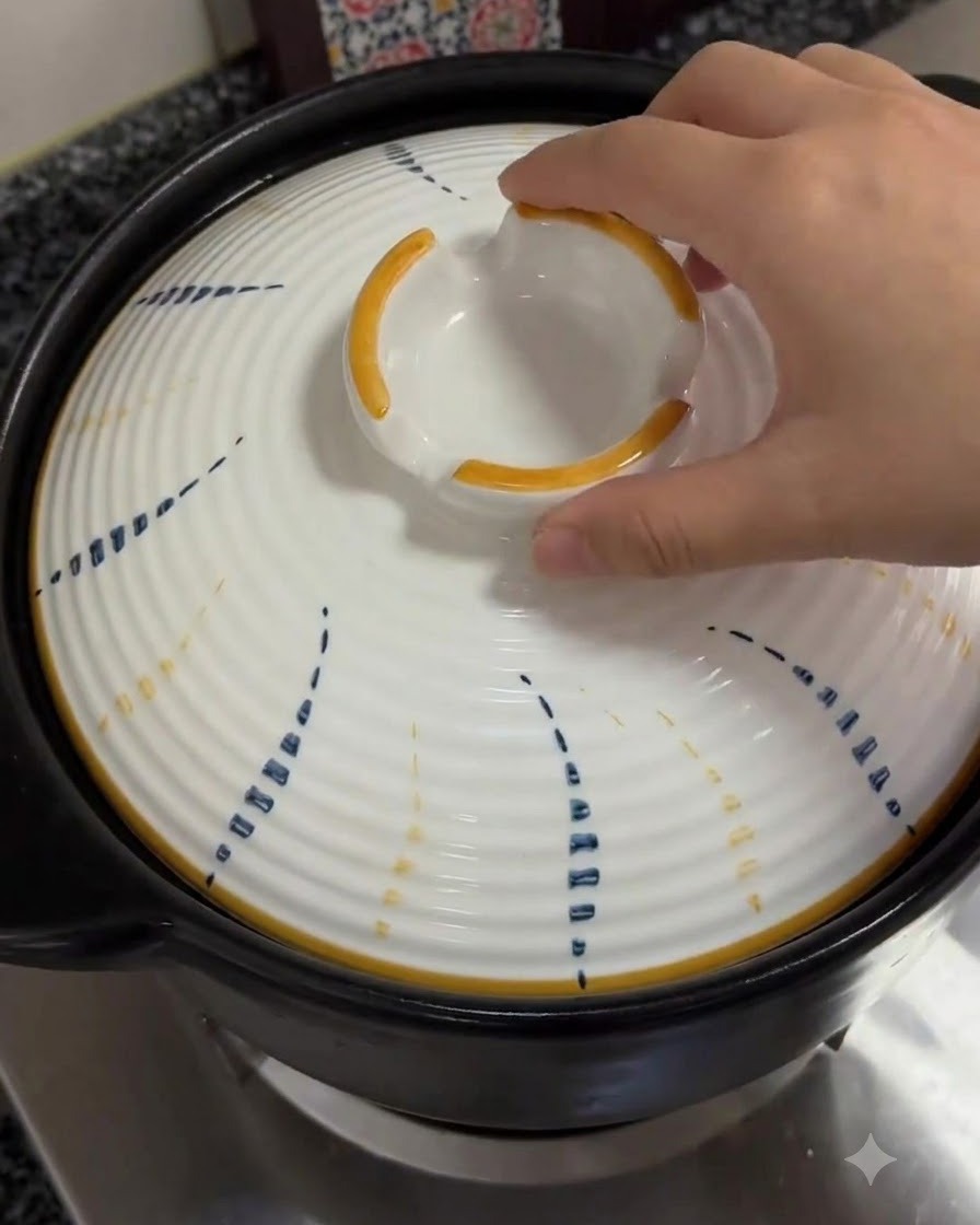 Une main replaçant le couvercle blanc à motifs sur la cocotte frémissante.