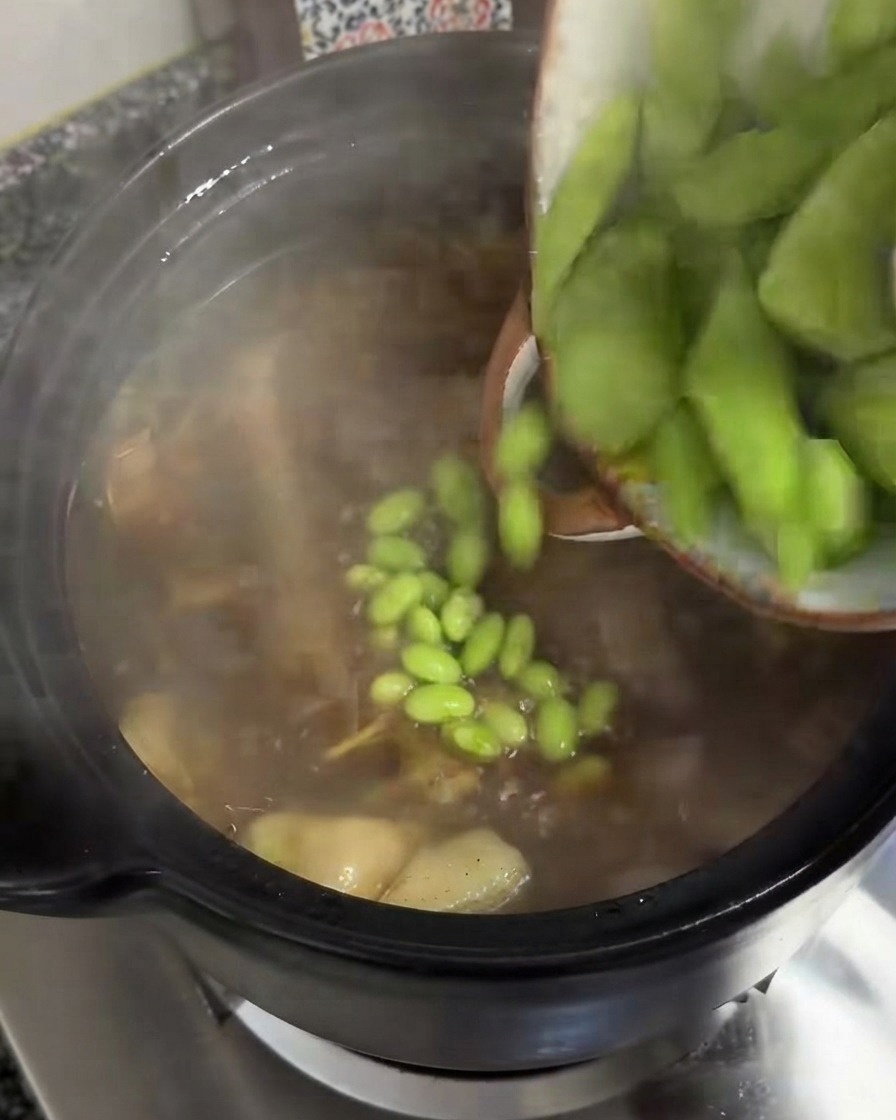Tranches épaisses de celtuce verte versées dun bol dans une marmite de soupe frémissante.