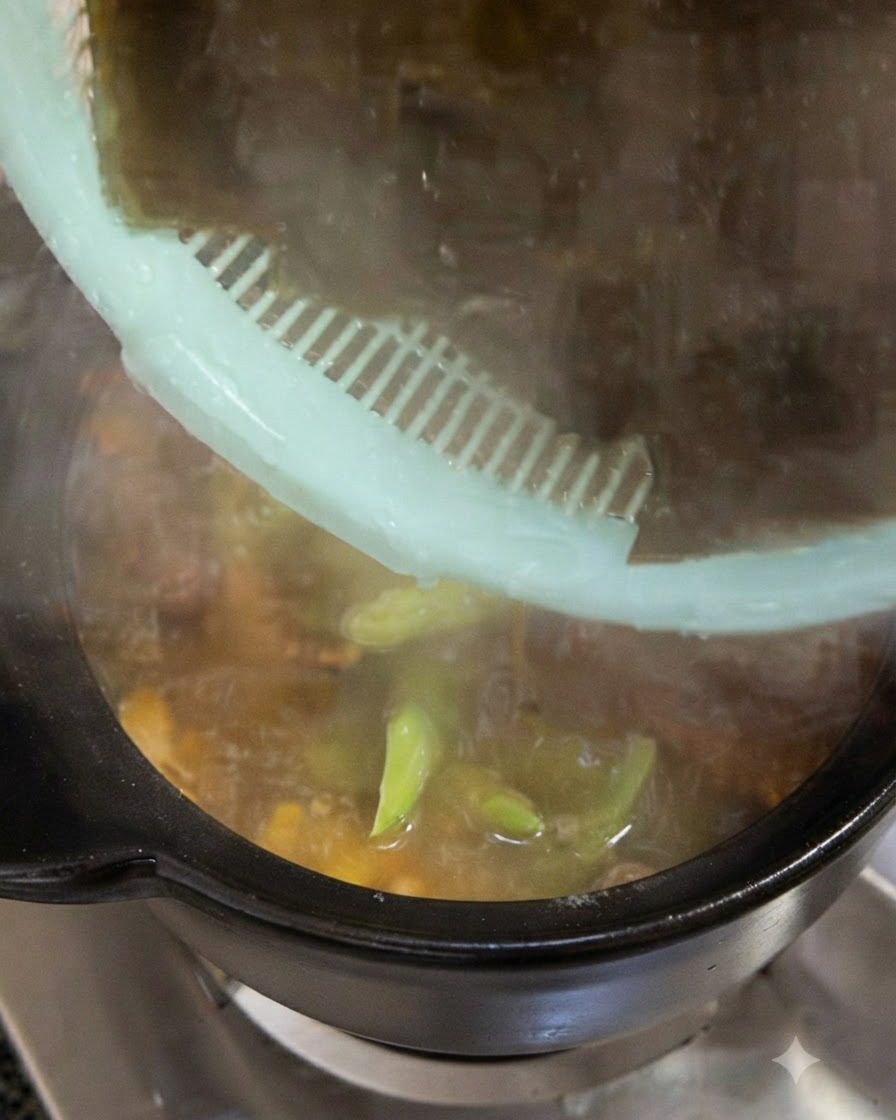 Gros morceaux dalgues vert foncé pré-trempées ajoutés dans la marmite de cuisson à partir dune passoire verte.