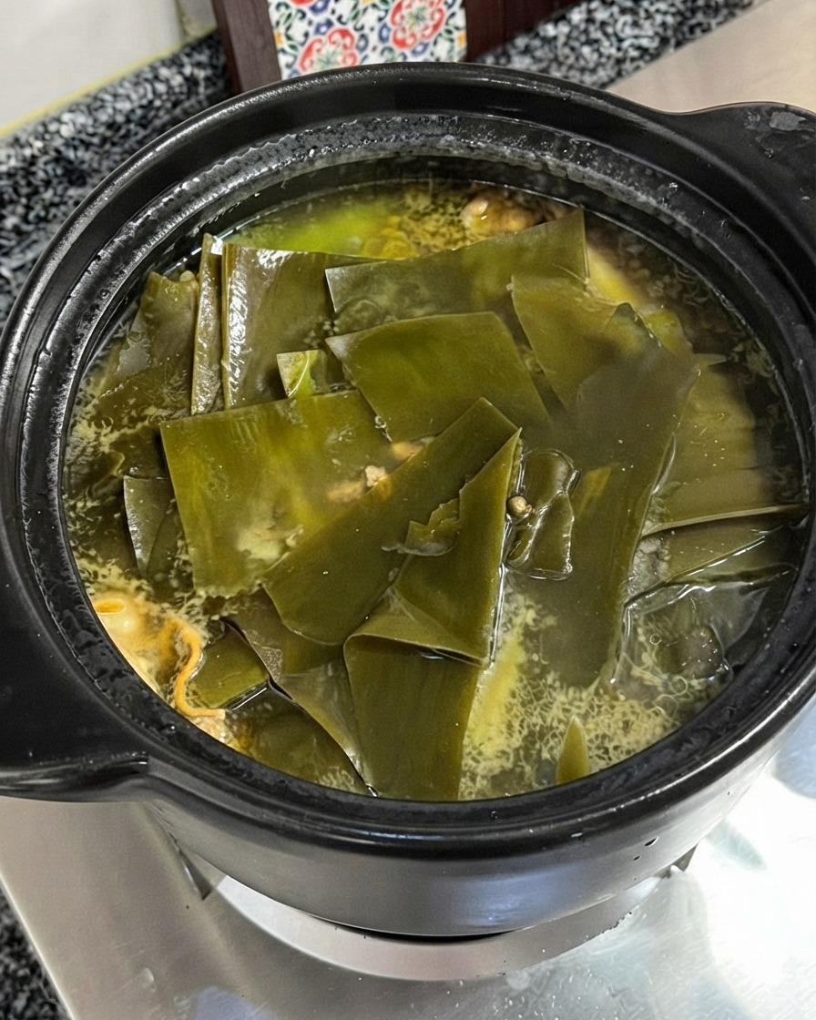 Poudre dassaisonnement de type bouillon de poulet ajoutée dans la soupe de poulet et dalgues frémissante.