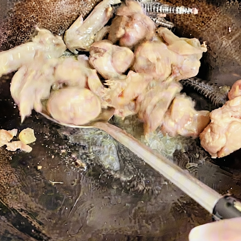 Morceaux de poulet retournés et sautés avec une spatule dans le wok jusquà ce quils soient légèrement dorés.