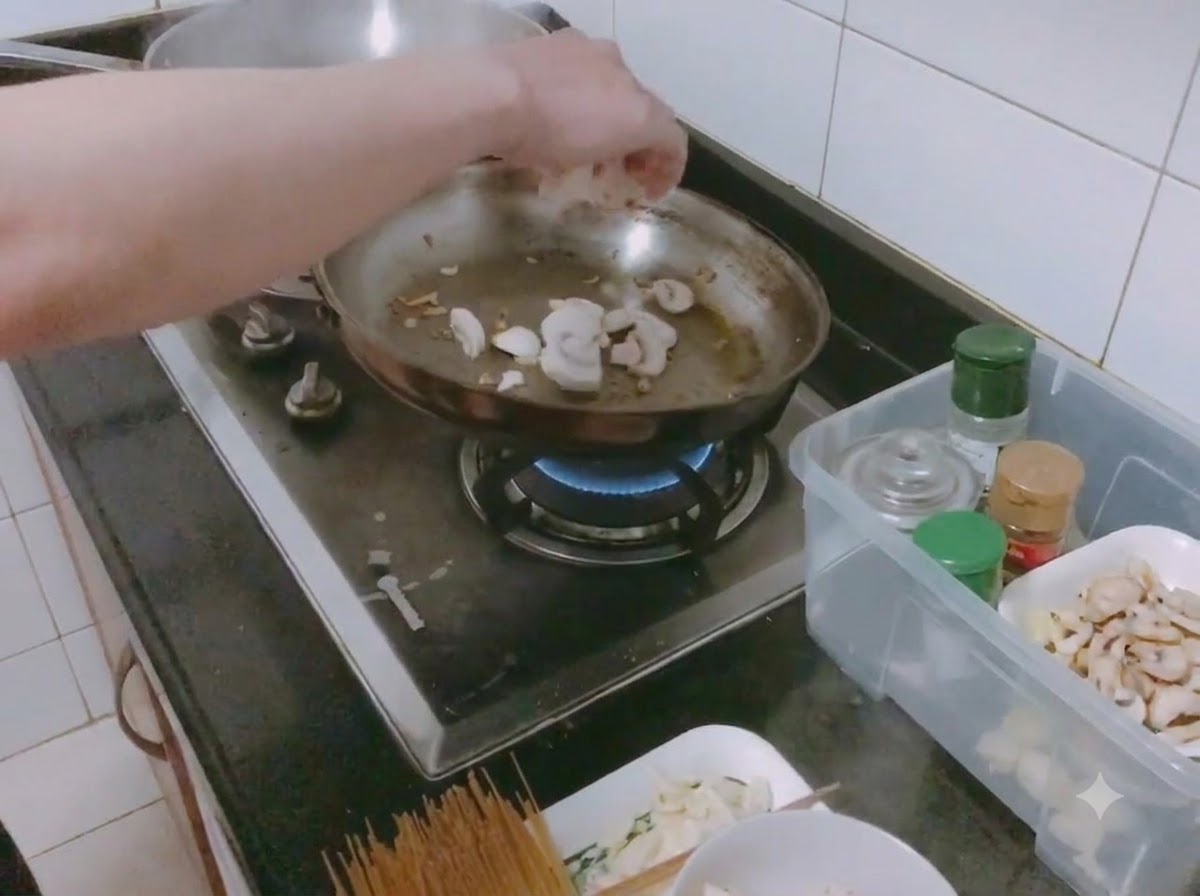 Des champignons émincés et des oignons hachés en train de revenir avec du sel dans une poêle.