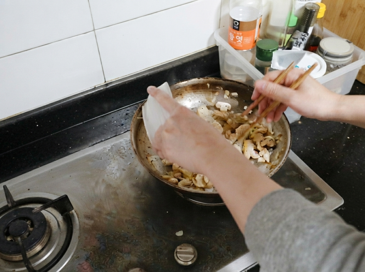 Des morceaux de poulet cuits replacés dans la poêle avec les champignons et les oignons.