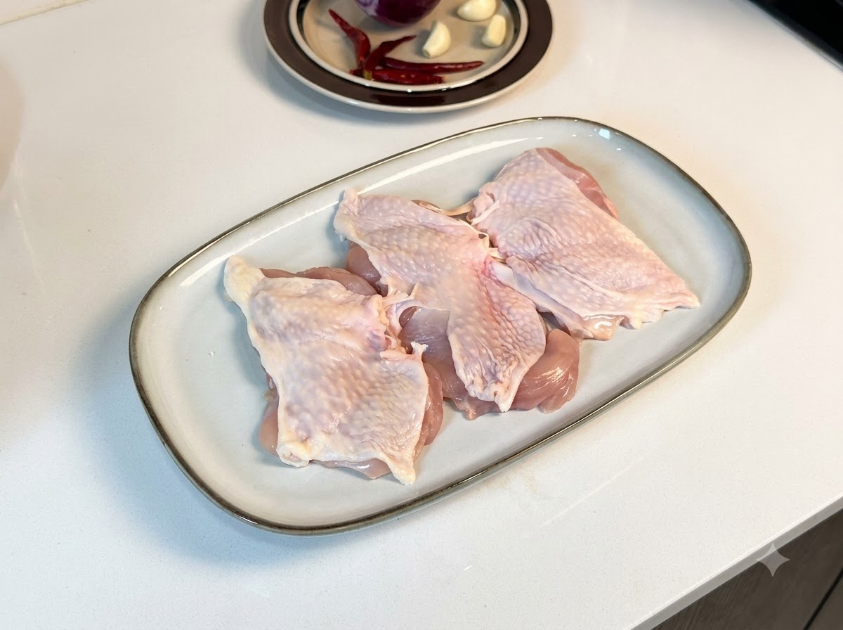 Hauts de cuisse de poulet désossés étalés sur une assiette blanche, enrobés de poivre noir et dépices.