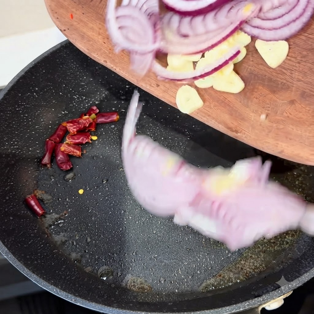 Lamelles doignon rouge, tranches dail et morceaux de piments secs ajoutés dans une poêle chaude.