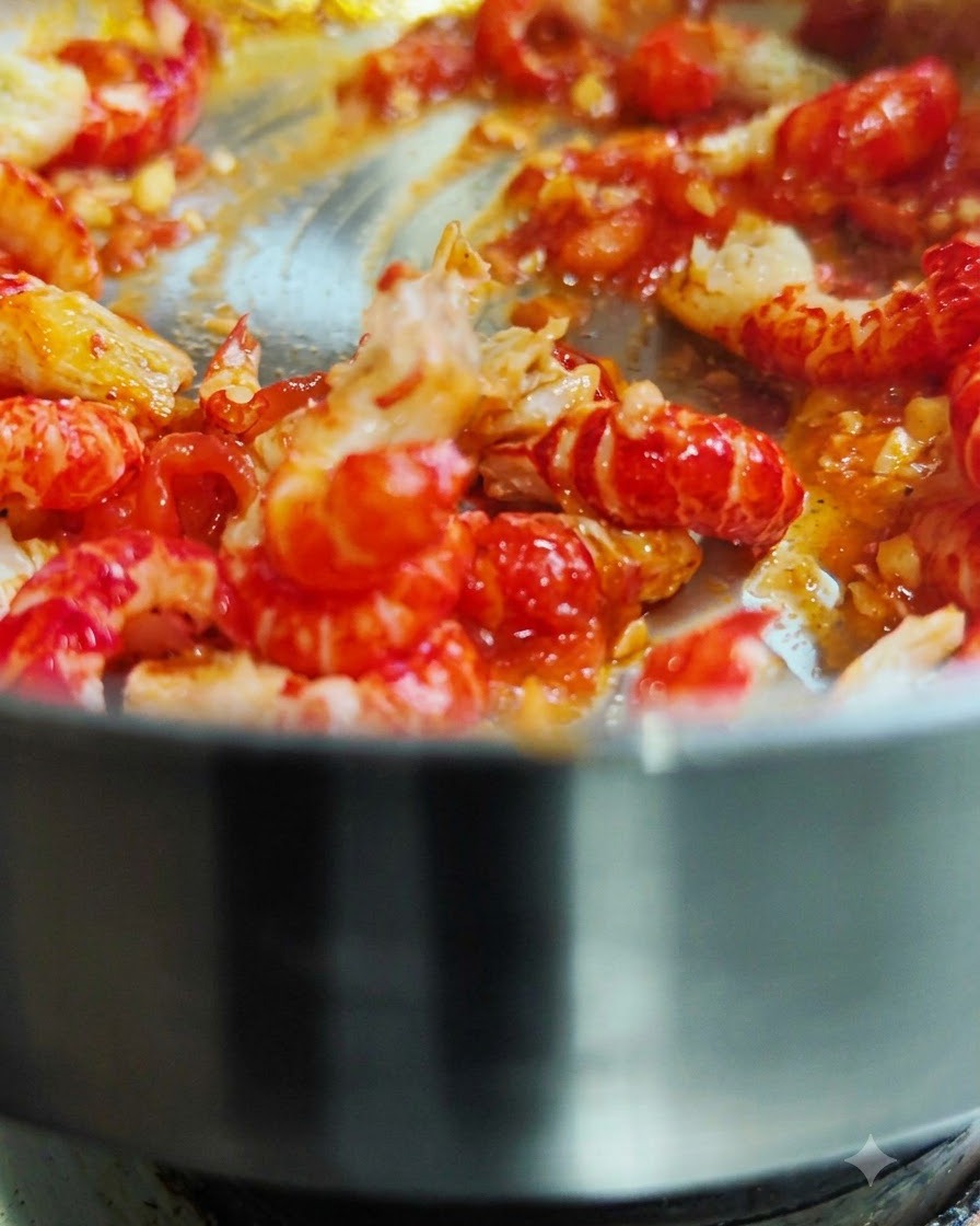 Queues décrevisses décortiquées en train dêtre mélangées et sautées dans une poêle chaude avec de la sauce tomate rouge.
