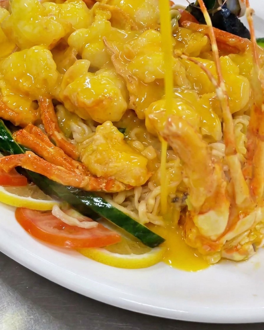 Verser les morceaux de homard frits dans un wok rempli dune sauce au fromage jaune riche et bouillante.