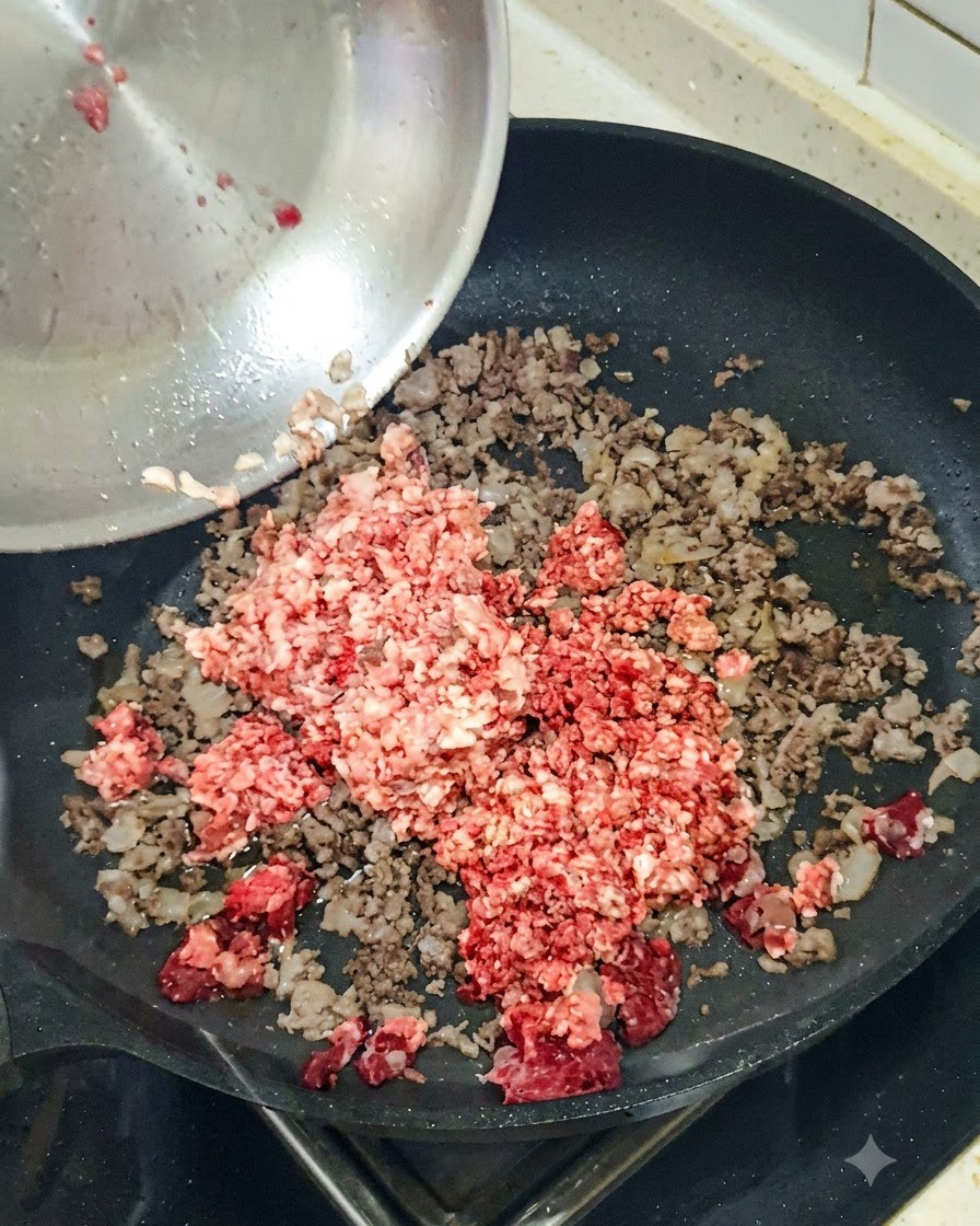 De loignon rouge haché jeté dans une poêle contenant la viande hachée dorée.