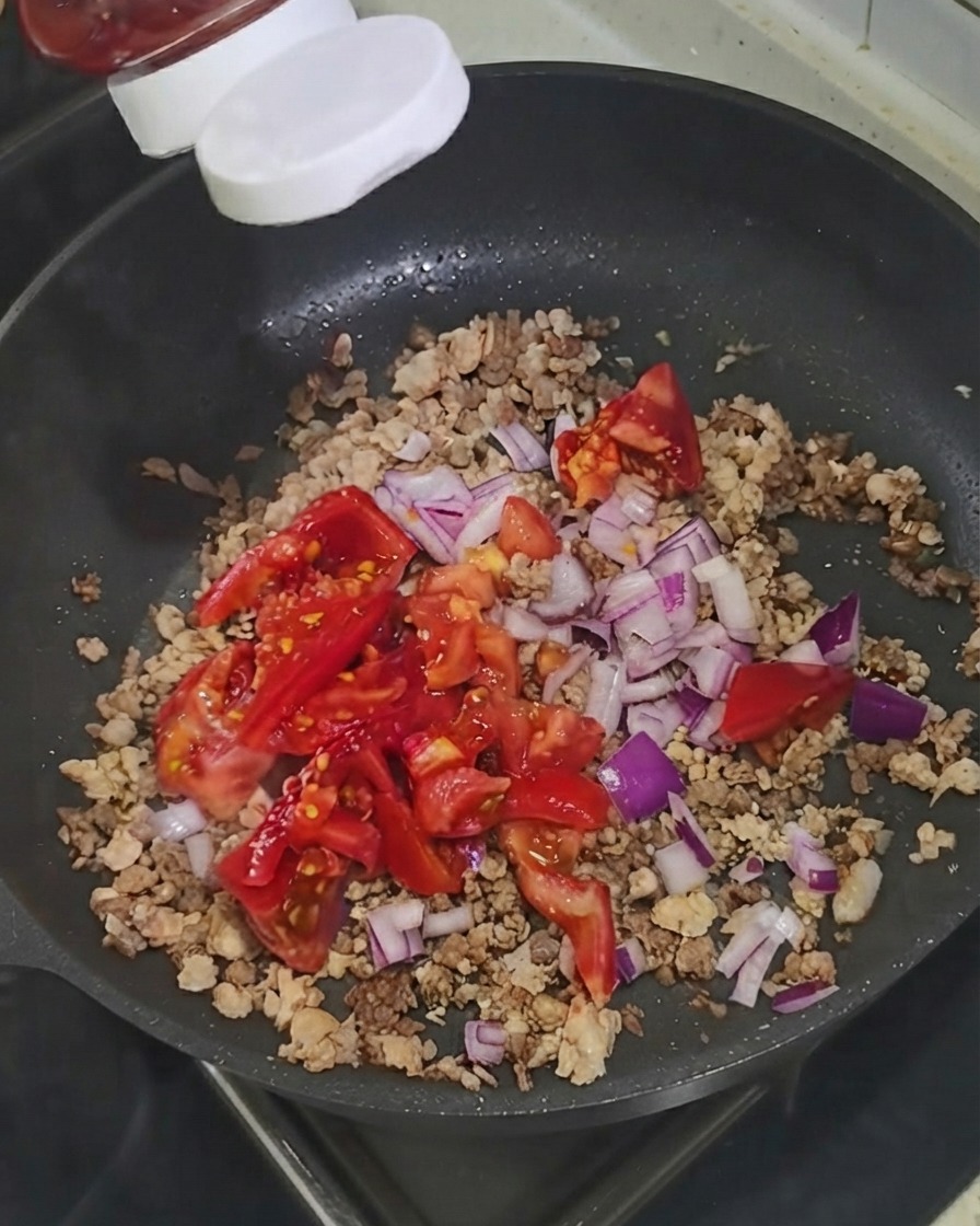 Du ketchup pressé dune bouteille directement sur les ingrédients dans la poêle.
