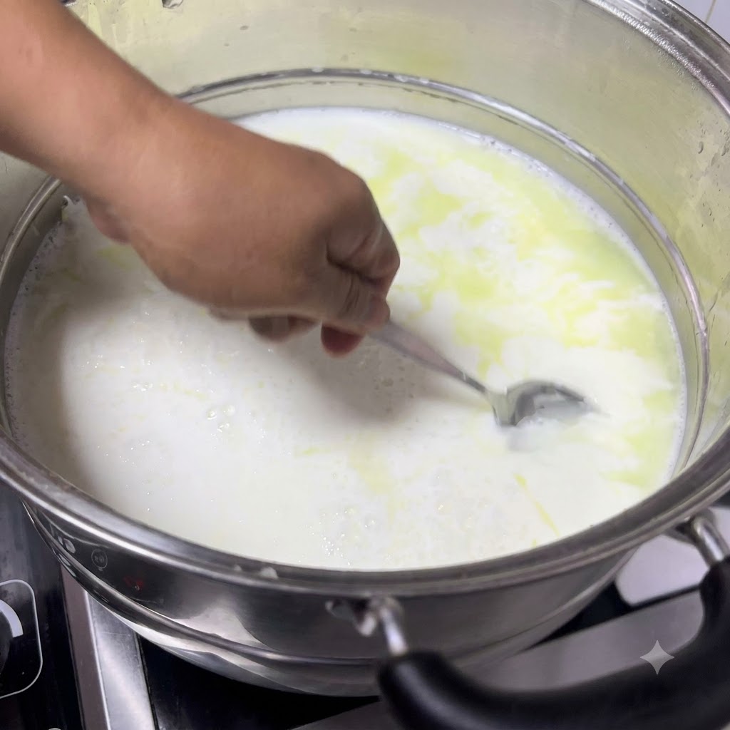 Une cuillere ramassant du lait caille de la casserole, montrant des cailles blancs et doux se separant du petit-lait jaunatre.