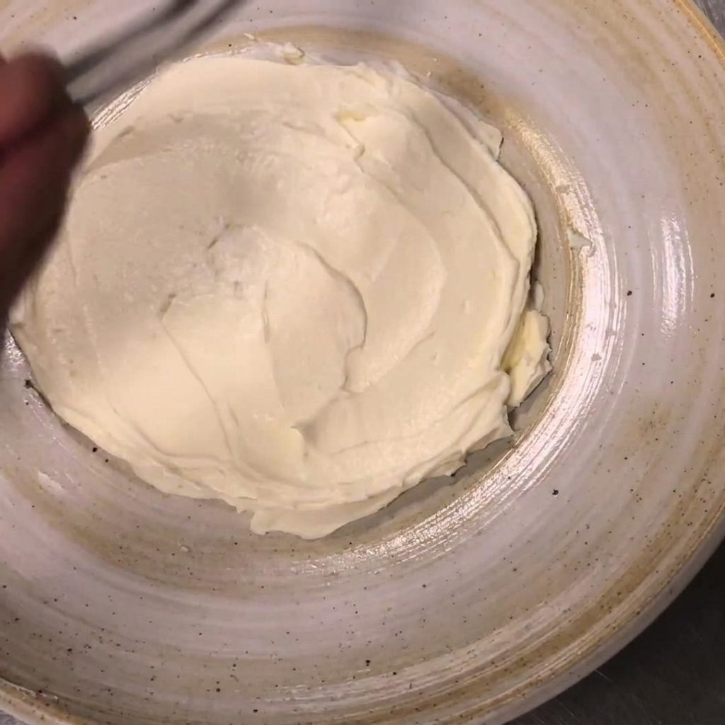 Moitiés de tomates cerises placées sur les bords de la ricotta étalée à laide de pinces.