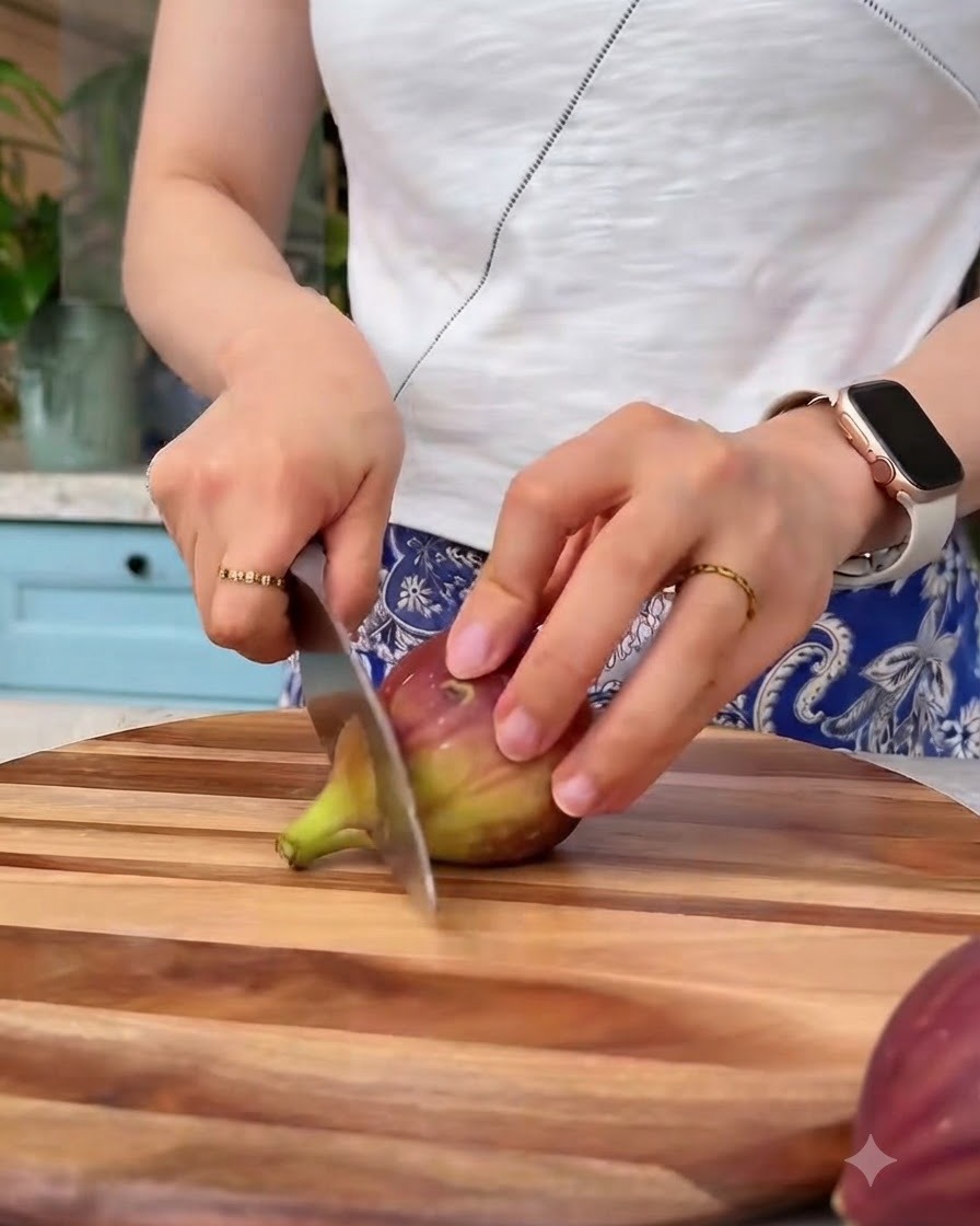 Figues fraîches coupées en petits morceaux avec un couteau sur une planche à découper en bois.