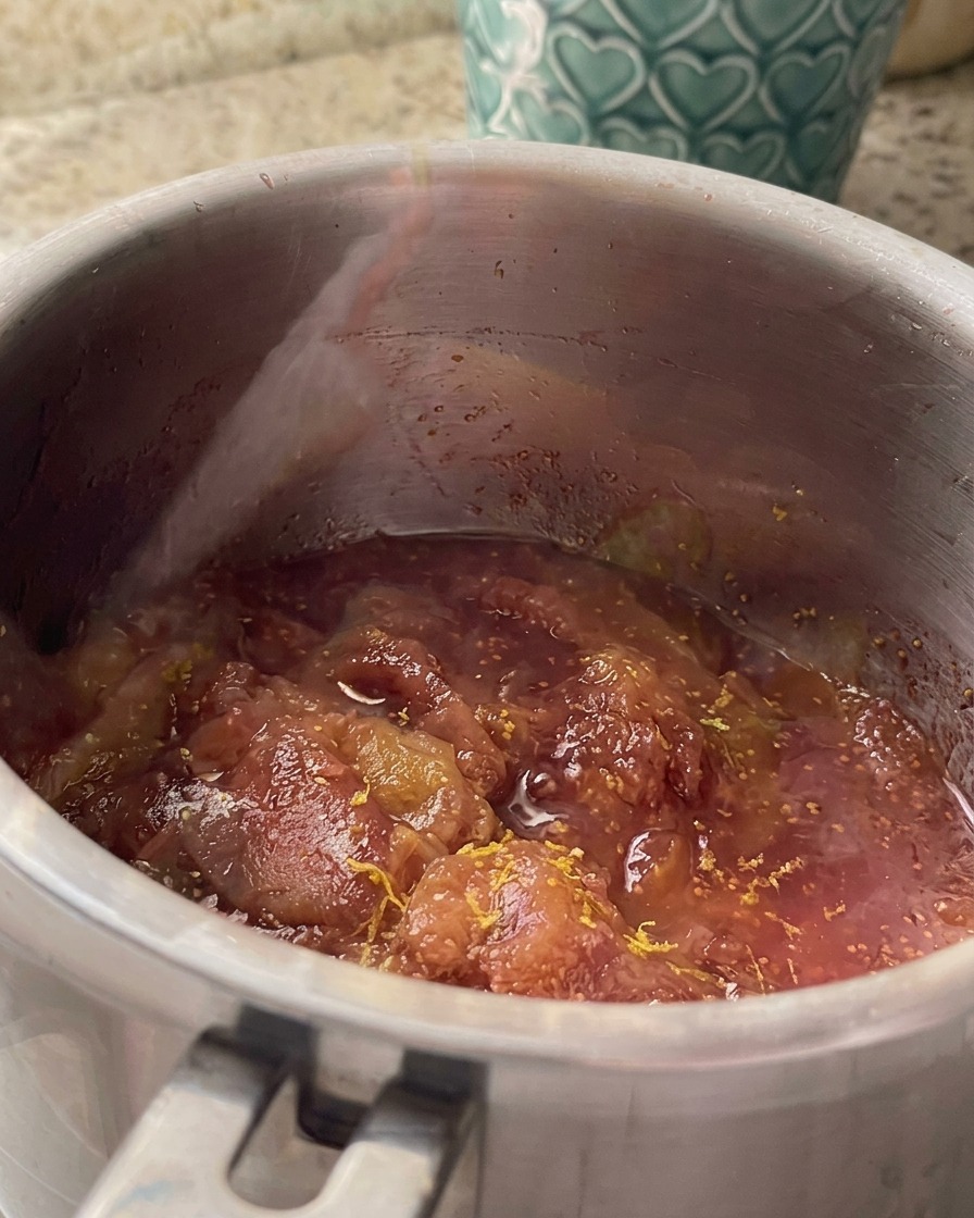 Zeste et jus de citron mélangés dans la sauce de figues mijotée dans une casserole en acier inoxydable.