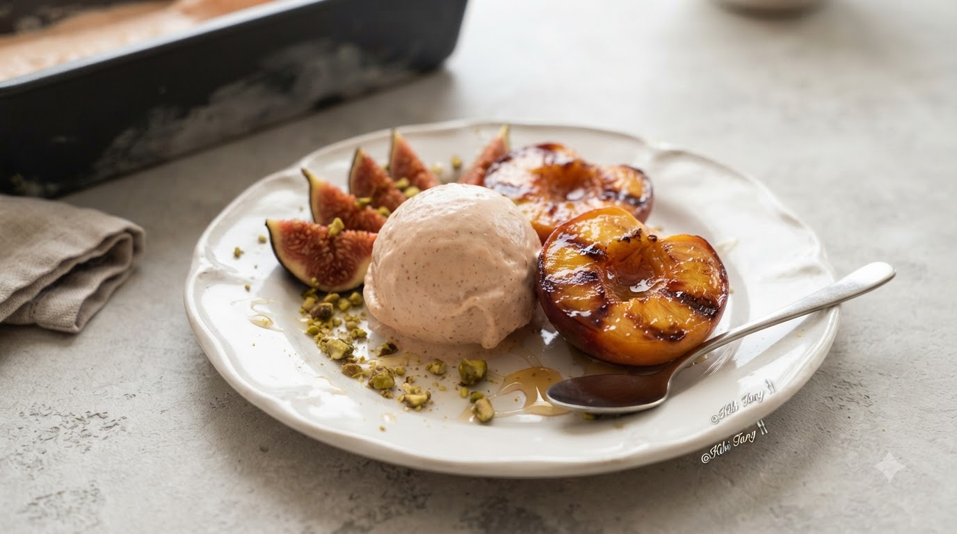 Une boule de gelato crémeuse aux figues et au rhum servie avec des moitiés de pêches chaudes rôties à la cannelle et des pistaches concassées.