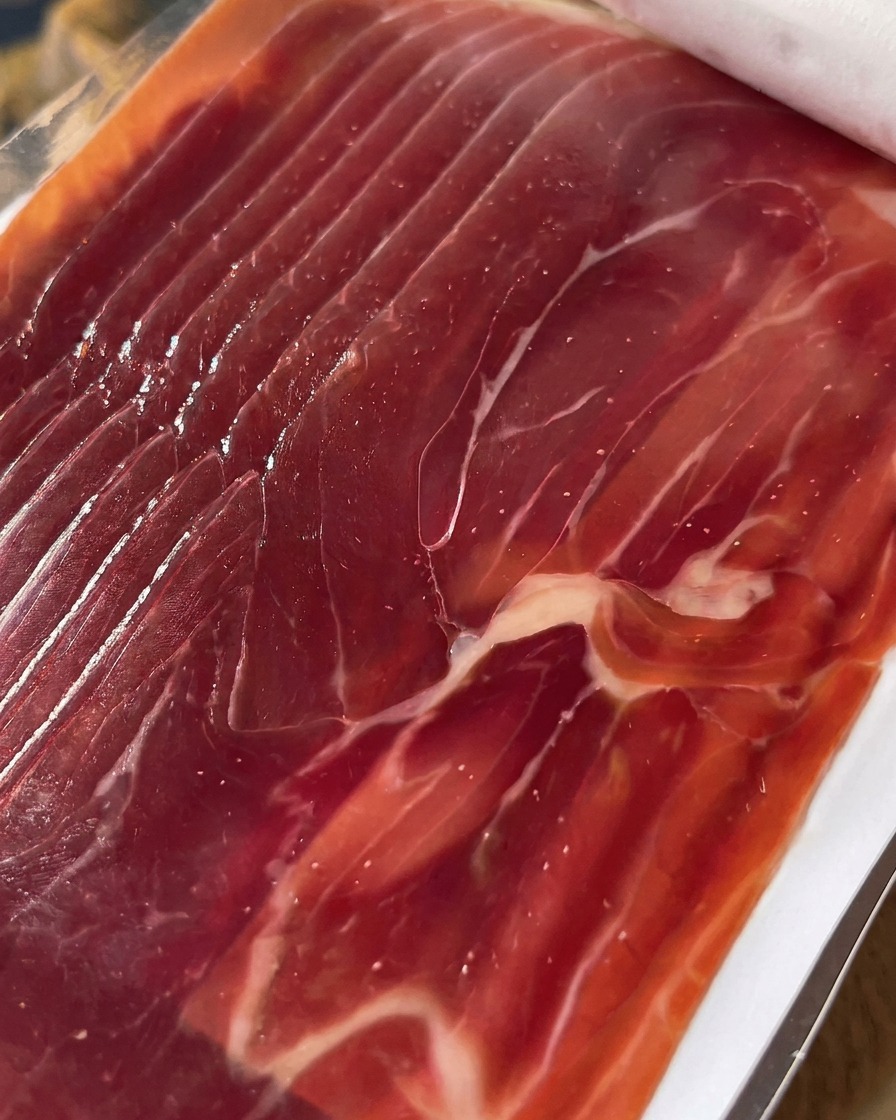Gros plan de tranches de prosciutto prêtes à être disposées sur les figues.