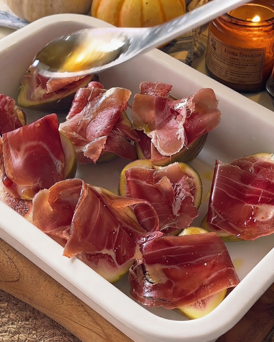 Du miel versé à la cuillère sur les figues et le prosciutto préparés dans un plat à four.