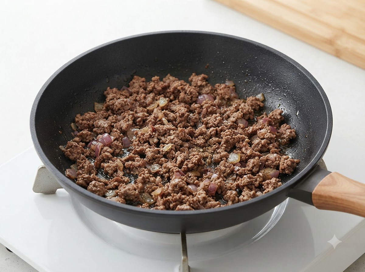 Du bœuf haché cuit et des oignons mélangés ensemble à lintérieur dune poêle.