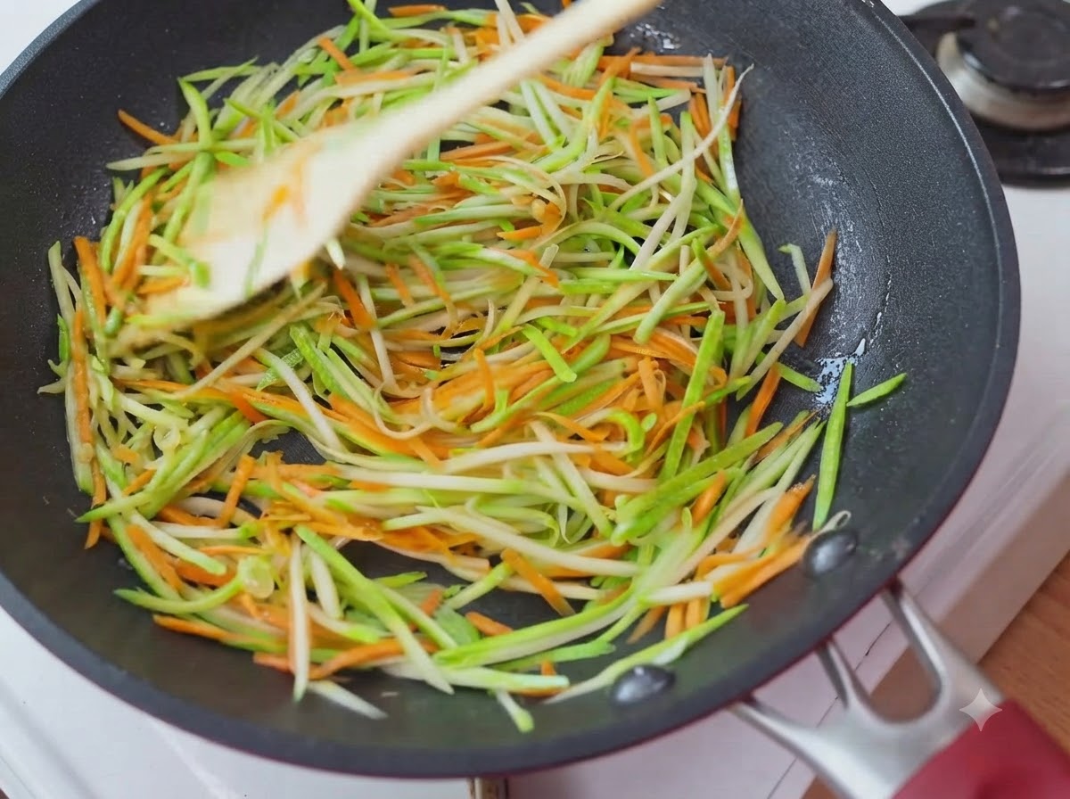 Des courgettes et carottes râpées réparties uniformément en couche circulaire à lintérieur de la poêle.