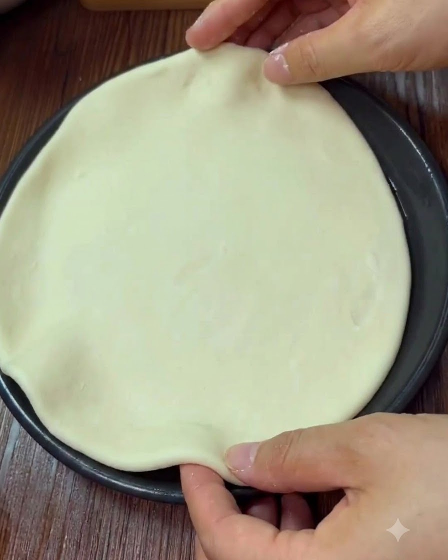 Mains façonnant et pinçant le bord dune pâte à pizza ronde dans un moule de cuisson.