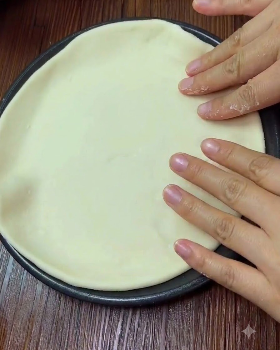Mains appuyant doucement sur la surface de la pâte à pizza aplatie.