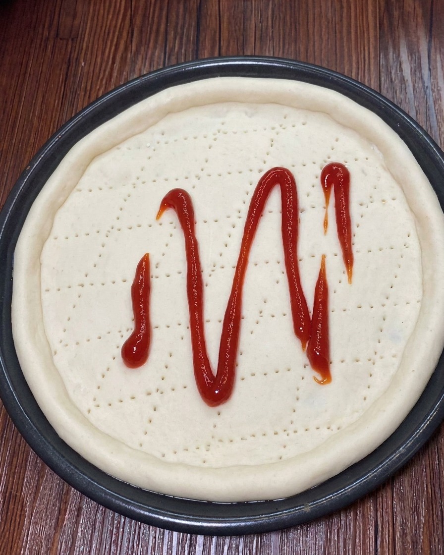 De la mozzarella râpée parsemée uniformément sur la sauce tomate de la pâte à pizza.
