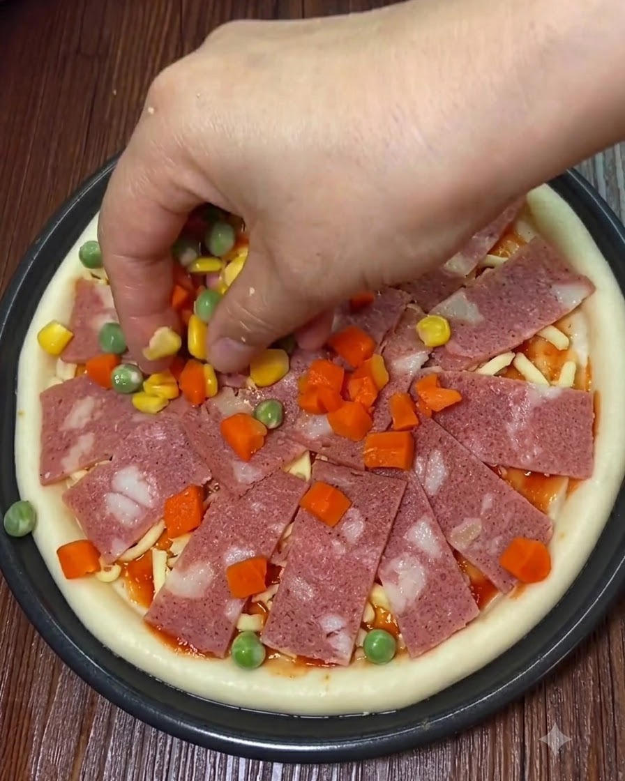 Tranches de bacon, maïs doux et dés de légumes déposés sur la pizza.