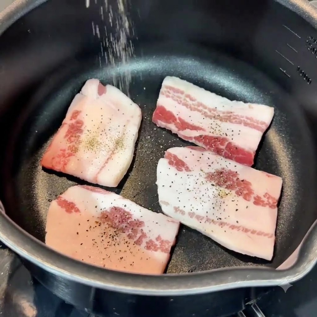 Sel et poivre saupoudrés den haut sur des tranches de poitrine de porc à lintérieur dune poêle.