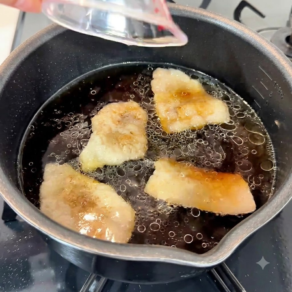 Pâte dail, huile de sésame et sucre blanc versés dans la riche base de soupe sombre dans une casserole.