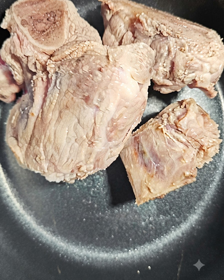 Une tranche de racine dangélique placée à côté des os de porc dans la cuve.