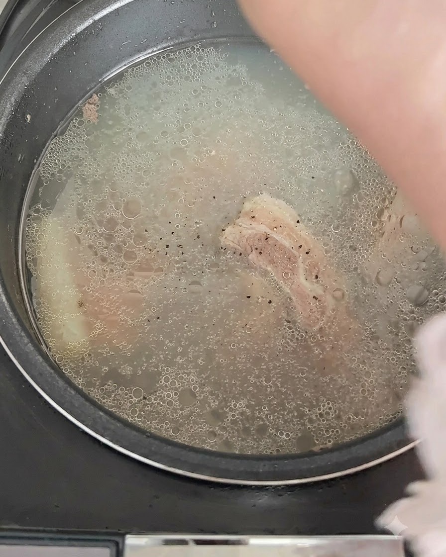 Du poivre noir saupoudré sur le bouillon frémissant dans le cuiseur de riz.