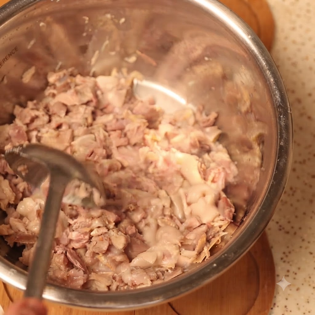 Viande de porc cuite soigneusement écrasée dans un grand bol à mélanger.