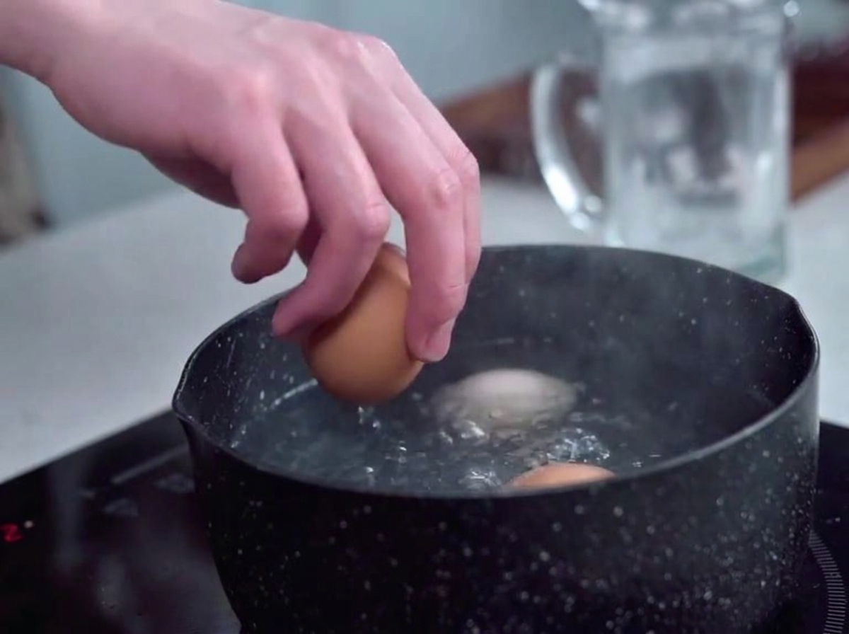 Œufs places delicatement dans une casserole deau bouillante a laide dune main.