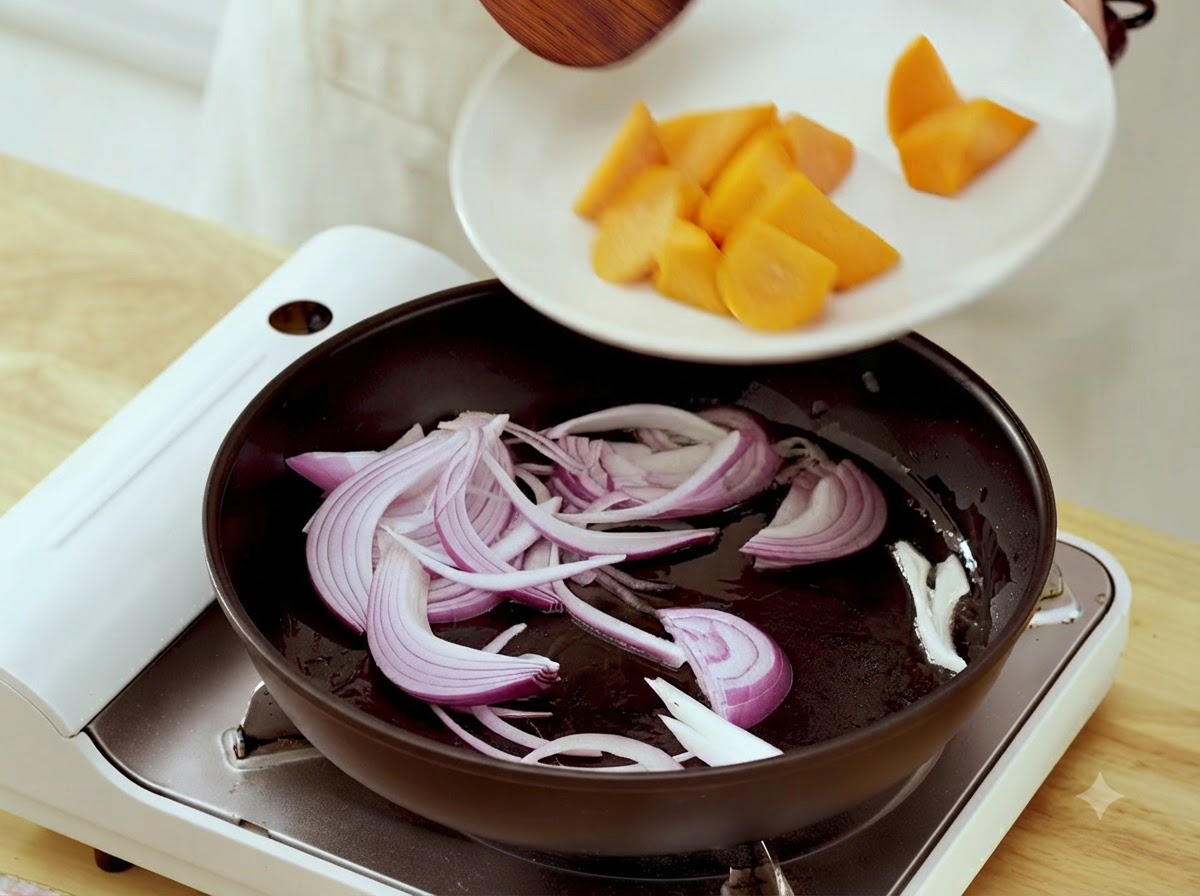 Des morceaux de carottes transférés dune assiette blanche vers une poêle contenant des lamelles doignon sautées.