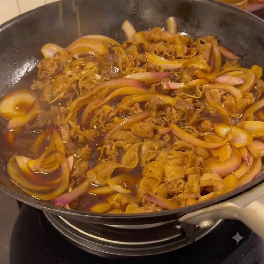 Du bœuf et des oignons mijotant dans une sauce teriyaki savoureuse foncée à lintérieur dune poêle à frire.