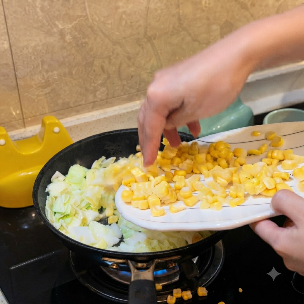 Une main versant des grains de maïs jaunes dune assiette blanche dans une poêle contenant du chou haché.